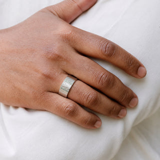 Man wearing the 8mm Viridian Leaf & Green Tourmaline men's wedding band in sterling silver, carved leaf panel framed by green tourmaline channels