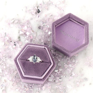 Adeline Marquise Cut Alexandrite Ring in Sterling Silver by Aquamarise displayed in a purple velvet hexagonal box surrounded by pastel pink crystal accents.